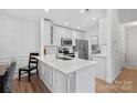 Modern kitchen with white cabinetry, stainless steel appliances, quartz countertops, and wood flooring at 9027 Mcdowell Creek Ct, Cornelius, NC 28031