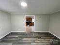 Living room featuring gray walls and flooring that looks into a kitchen with wooden cabinets and stainless appliances at 1404 Linwood Rd, Gastonia, NC 28052