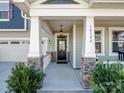 Inviting front entryway with stone column accents and covered porch leading to a modern door at 14106 Magnolia Walk Dr, Huntersville, NC 28078