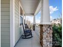 Relaxing front porch with rocking chairs, stone columns, and views of the surrounding neighborhood at 14106 Magnolia Walk Dr, Huntersville, NC 28078