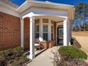 Inviting covered front porch with decorative columns, a cozy seating area, and lush landscaping at 21222 W Tern Ct, Fort Mill, SC 29707