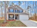 Two story house with gray siding, white garage door, and rocking chairs on the porch at 5510 Brickstone Dr, Charlotte, NC 28227