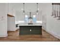 Modern kitchen with white cabinetry, dark island, stainless steel appliances, and pendant lighting at 718 Barrel Aly, Fort Mill, SC 29715