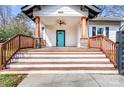 Inviting front porch with wooden steps, decorative pillars, and a bright blue door at 8228 Moores Chapel Rd, Charlotte, NC 28214