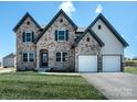 Two-story home features stone and siding, two-car garage, and a well-manicured lawn at Lot 1 Mayes Meadow Dr # Magnolia, Cornelius, NC 28078