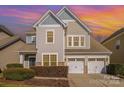 Two-story home featuring neutral siding, a three-car garage, manicured landscaping, under a colorful sky at 10149 Elizabeth Crest Ln, Charlotte, NC 28277