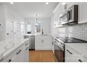 Modern kitchen with white cabinets, gray tile backsplash, and stainless steel appliances at 1122 Pegram Crossing Dr, Charlotte, NC 28205