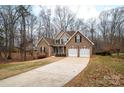 A brick two-story home featuring a two-car garage and long driveway surrounded by trees during the winter season at 122 Ardmore Pl, Mooresville, NC 28117