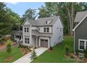 Landscaped two-story home with light-colored siding, a dormer, covered entry, attached one-car garage, and lush green lawn at 1912 St John St, Charlotte, NC 28216