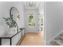 Inviting foyer with light hardwood floors, a decorative mirror, console table and a clear view of the front door at 1912 St John St, Charlotte, NC 28216