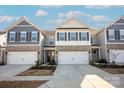 Inviting townhome exteriors showcasing coordinated designs, stone accents, and spacious driveways under a bright, partly cloudy sky at 4134 Steel Way, Sherrills Ford, NC 28673