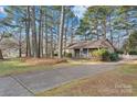 Scenic view of a single story home showing the driveway leading up to the house through a tree filled yard at 709 Falls Church Rd, Charlotte, NC 28270