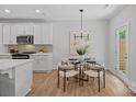 Eat-in kitchen with stainless appliances, white cabinets, and a modern lighting fixture at 19765 Feriba Pl, Cornelius, NC 28031