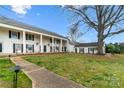 Stately white two-story home featuring black shutters, rocking chairs on the covered porch, and a beautiful large lawn at 7000 Quail Hill Rd, Charlotte, NC 28210