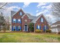 Attractive brick home with blue shutters and a well-maintained lawn at 7705 Windsor Forest Pl, Harrisburg, NC 28075