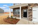 Inviting front porch adorned with stone accents and a black front door at 1730 Falls Cove Rd, Newton, NC 28658