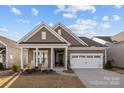 Charming home boasts a covered porch with rocking chairs, complemented by a well-maintained lawn and a two-car garage at 240 Portrait Way # 87, Indian Trail, NC 28079
