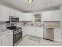 A well-lit kitchen with stainless steel appliances, white cabinets, and stone countertops at 3843 Foxford Pl, Charlotte, NC 28215