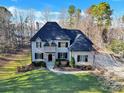 Stunning two-story home with dark shutters, a stone entrance, a well-manicured lawn, and mature trees at 107 E Cold Hollow Farms Dr, Mooresville, NC 28117