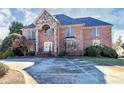 Elegant brick home featuring a stone facade, arched entryway, and a spacious driveway leading to the front entrance at 4029 Wild Nursery Ct, Charlotte, NC 28215