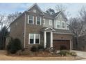 Two-story home with brick and gray siding with well-manicured landscaping and a two car garage at 1124 Greenbridge Dr, Matthews, NC 28105