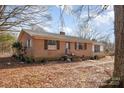 Charming brick home with a metal roof and cozy shutters nestled on a leaf-covered lot at 13501 Mullis Rd, Midland, NC 28107