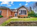 Charming brick home featuring a cozy sunroom with large windows and beautifully landscaped front yard at 8405 Olde Troon Dr # 4A, Charlotte, NC 28277