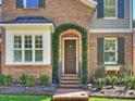 Inviting front entry with brick facade, arched door, and lush greenery at 6819 Conservatory Ln, Charlotte, NC 28210