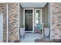 Inviting front porch with stonework, dark door, and potted plants at 8119 Merryvale Ln, Charlotte, NC 28214