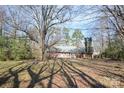 A view of the home's rear exterior with a wooden deck, surrounded by mature trees at 3303 Reid Cir, Monroe, NC 28112