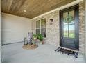 Inviting covered porch with brick accents, a rocking chair, and a welcoming entrance at 3428 Greene Rd, Monroe, NC 28110