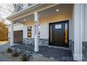 Inviting front porch with stone flooring, a black front door, and white columns at 4827 Brookridge Ne Dr, Hickory, NC 28601