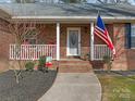 Close up of charming front porch with American flag and tasteful landscaping at 5904 Bryant Ln, Waxhaw, NC 28173