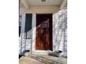 Inviting front entrance showcasing a beautiful wood door flanked by decorative potted plants and white siding at 7860 Georgia Ave, Kannapolis, NC 28081