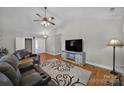 Bright living room featuring vaulted ceiling, hardwood floors, and a large television at 849 Treva Anne Sw Dr, Concord, NC 28027