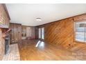 Living room with hardwood floors, brick fireplace and wood paneling at 1308 Gum Branch Rd, Charlotte, NC 28214