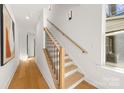 Bright entryway with wooden staircase, modern black railing, and light hardwood floors at 3132 Carol Ave, Charlotte, NC 28208