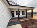 Charming front porch with black columns and railing, brick steps, and a black front door at 106 Gilliatt St, Shelby, NC 28150