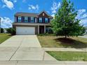 Charming two-story home featuring a two-car garage, brick accents, and a large tree in the yard at 121 Mackinac Dr, Mooresville, NC 28117