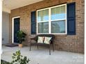 Inviting front porch with a decorative bench, brick facade, and blue door and shutters at 121 Mackinac Dr, Mooresville, NC 28117