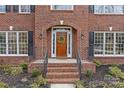 Charming brick home entrance with an arched doorway, black shutters and manicured landscaping at 2050 Stoney Creek Nw Dr, Concord, NC 28027