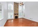 Living room featuring a stone fireplace, large windows, hardwood floors, and high ceilings at 2327 Axford Ln, Matthews, NC 28105