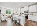 Modern kitchen featuring an island with bar stool seating and a view into the living room at 3038 Finchborough Ct # 234, Charlotte, NC 28269
