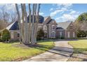 Classic two-story home with brick facade, mature trees, and a paved driveway leading to the residence at 4316 Mourning Dove Dr, Matthews, NC 28104