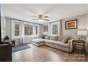 Bright living room featuring a large sectional sofa, wood-look flooring, and multiple windows at 5483 Paulmo Dr, Charlotte, NC 28216