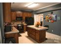 Kitchen features wood cabinets, an island, and black appliances at 5711 Falls Ridge Ln, Charlotte, NC 28269