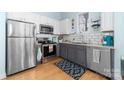 A well-lit kitchen featuring stainless steel appliances, white cabinets, gray lower cabinets, and a window at 780 N Davidson St, Charlotte, NC 28202