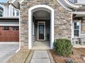 Close-up of a stone-covered front porch with an arch, featuring a seating area and wooden front door at 9730 Briarwick Ln, Charlotte, NC 28277