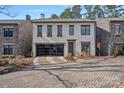 Charming two-story home featuring a glass garage door, brick driveway, and stone accents at 220 Ambleside Village Ln, Davidson, NC 28036