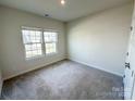 Well-lit bedroom with neutral carpet and walls, and a large window offering natural light at 5047 Summer Surprise Ln, Charlotte, NC 28215